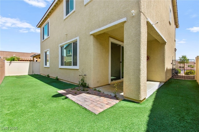 rear view of property with a fenced backyard, a patio, stucco siding, and a yard