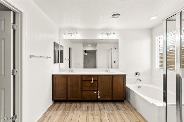 full bath featuring double vanity, a ceiling fan, a bath, a shower stall, and a sink