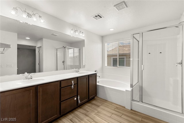 bathroom featuring a sink, wood finished floors, visible vents, a garden tub, and a stall shower
