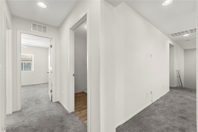 corridor featuring carpet floors, baseboards, and visible vents