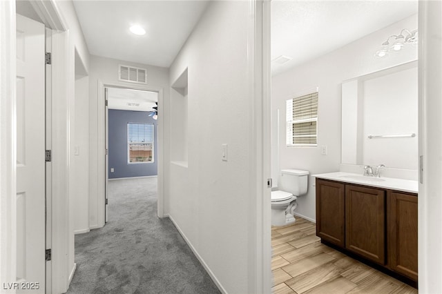 hall with a sink, baseboards, and visible vents
