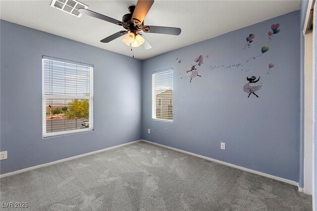 carpeted spare room with visible vents, baseboards, and ceiling fan