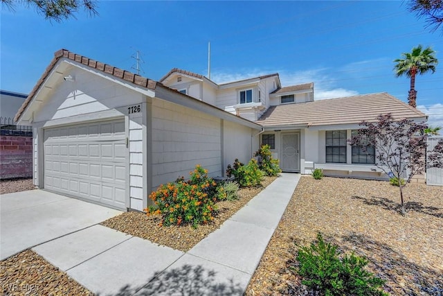 traditional-style home featuring driveway, a tile roof, and an attached garage