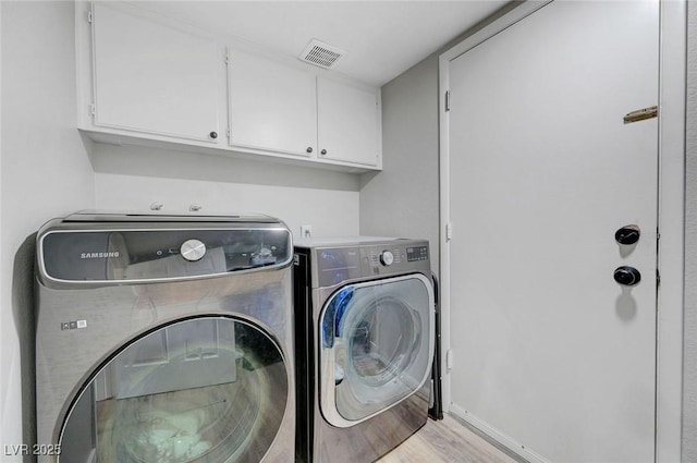 washroom featuring cabinet space, wood finished floors, visible vents, separate washer and dryer, and baseboards