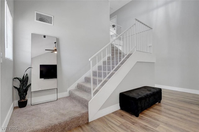 staircase with baseboards, a ceiling fan, and visible vents
