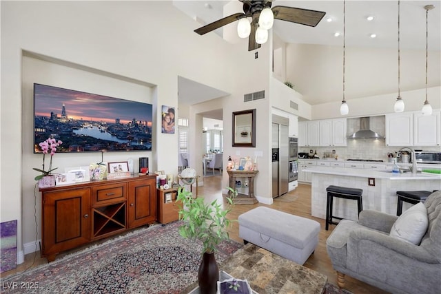 2909 Sterling Cove Dr, Las Vegas, NV 89128 - living area featuring visible vents, baseboards, a high ceiling, a ceiling fan, and light wood-style flooring