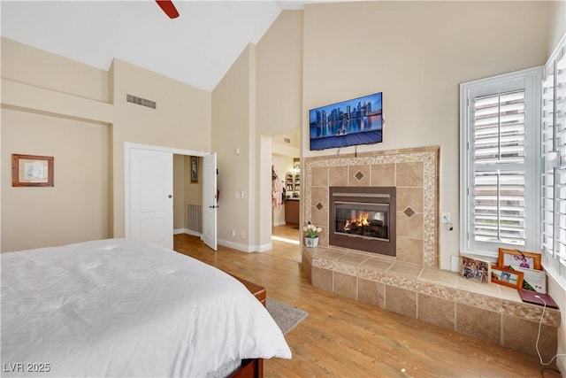 2909 Sterling Cove Dr, Las Vegas, NV 89128 - bedroom featuring wood finished floors, high vaulted ceiling, a tile fireplace, and ceiling fan