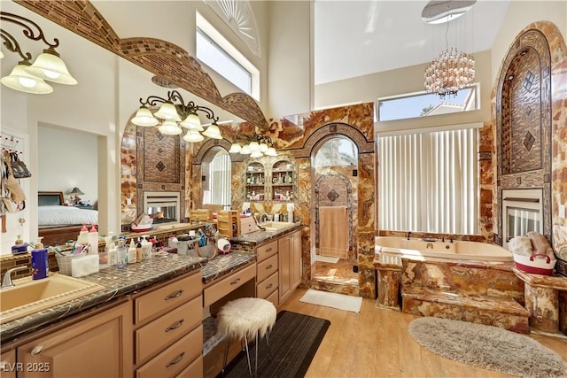2909 Sterling Cove Dr, Las Vegas, NV 89128 - bathroom with vanity, an inviting chandelier, wood finished floors, a high ceiling, and a multi sided fireplace