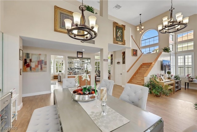2909 Sterling Cove Dr, Las Vegas, NV 89128 - dining space featuring a towering ceiling, visible vents, light wood-type flooring, stairway, and an inviting chandelier