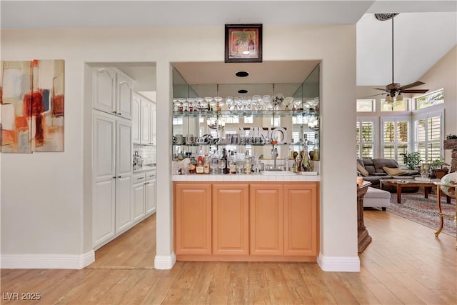 2909 Sterling Cove Dr, Las Vegas, NV 89128 - bar with decorative backsplash, a ceiling fan, wet bar, baseboards, and light wood finished floors