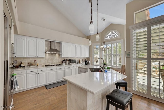2909 Sterling Cove Dr, Las Vegas, NV 89128 - kitchen featuring gas cooktop, a sink, wall chimney exhaust hood, stainless steel microwave, and a kitchen bar