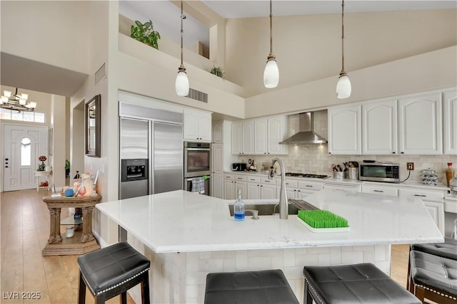 2909 Sterling Cove Dr, Las Vegas, NV 89128 - kitchen with a towering ceiling, appliances with stainless steel finishes, a sink, a breakfast bar, and wall chimney exhaust hood