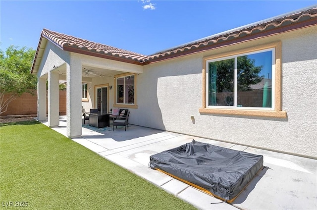 back of house with ceiling fan, stucco siding, a patio area, a lawn, and a tile roof