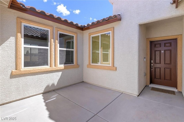 property entrance featuring a tiled roof, a patio area, and stucco siding