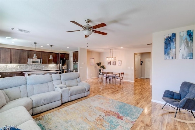 living room featuring ceiling fan, visible vents, light wood-type flooring, baseboards, and recessed lighting