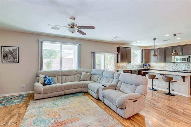 living area featuring visible vents, baseboards, recessed lighting, a ceiling fan, and light wood-style flooring