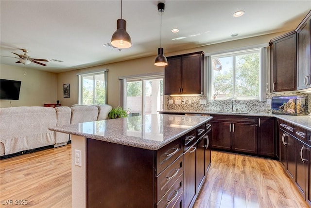 kitchen with a sink, open floor plan, light wood-style flooring, and a kitchen island