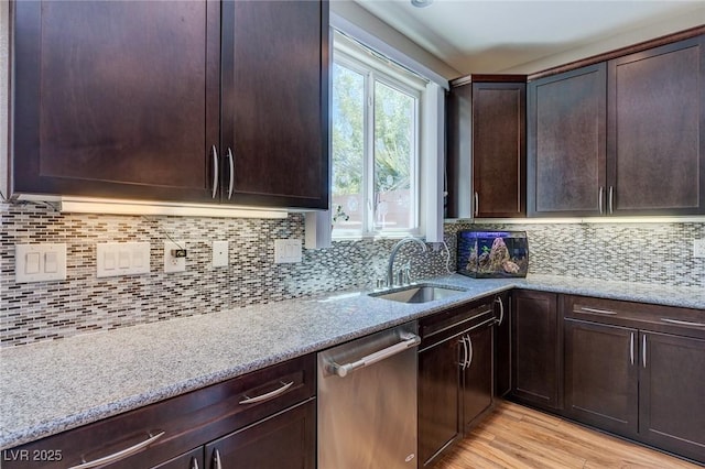 kitchen featuring stainless steel dishwasher, dark brown cabinetry, light stone counters, a sink, and backsplash