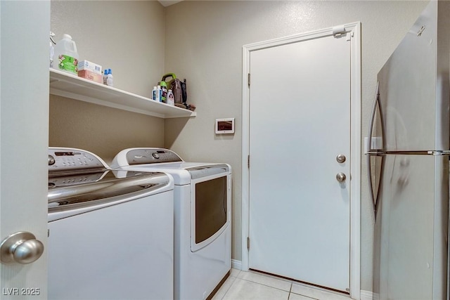 clothes washing area featuring laundry area, washer and clothes dryer, and light tile patterned flooring