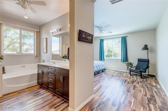 bathroom featuring ceiling fan, visible vents, wood finished floors, and a bath