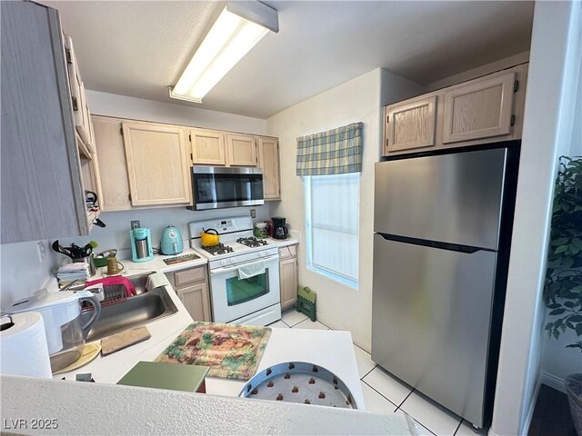 698 S Racetrack Rd Unit 322, Henderson, NV 89015 - kitchen featuring light brown cabinetry, a sink, light countertops, stainless steel appliances, and light tile patterned floors