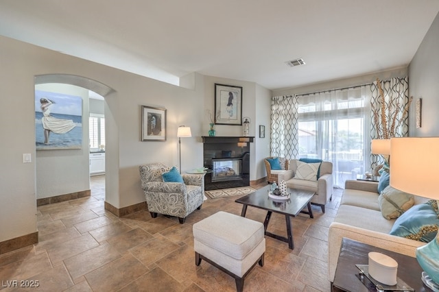 living area with arched walkways, baseboards, visible vents, and a wealth of natural light