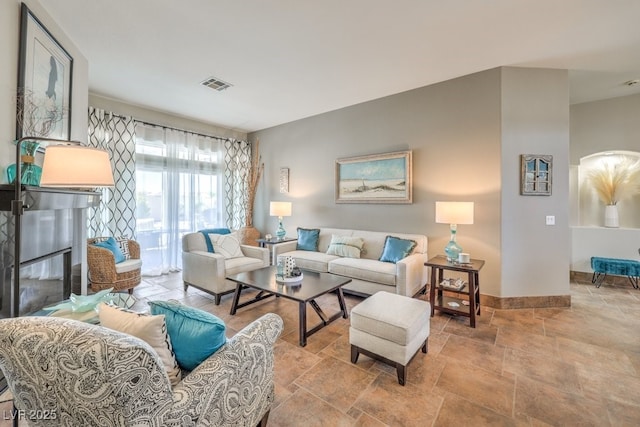 living area featuring stone finish flooring, baseboards, and visible vents