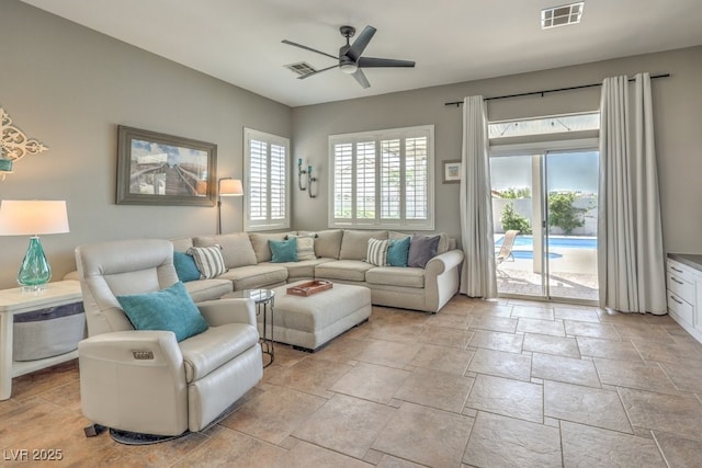 living room with stone tile floors, a ceiling fan, and visible vents