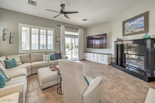 living room with visible vents, a ceiling fan, and stone finish flooring