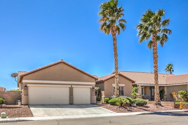 mediterranean / spanish home featuring an attached garage, stucco siding, a tiled roof, and concrete driveway
