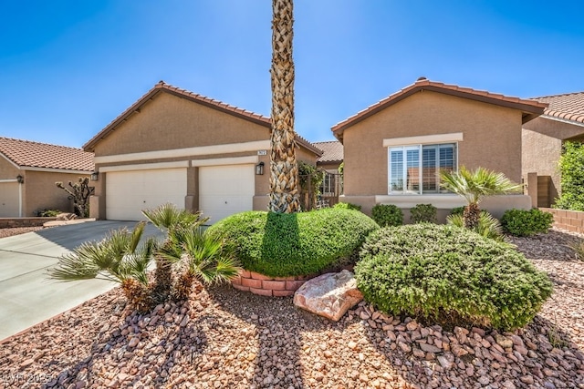 view of front facade with stucco siding, a tiled roof, driveway, and a garage