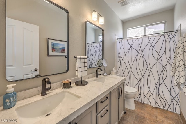 full bathroom featuring double vanity, toilet, visible vents, and a sink