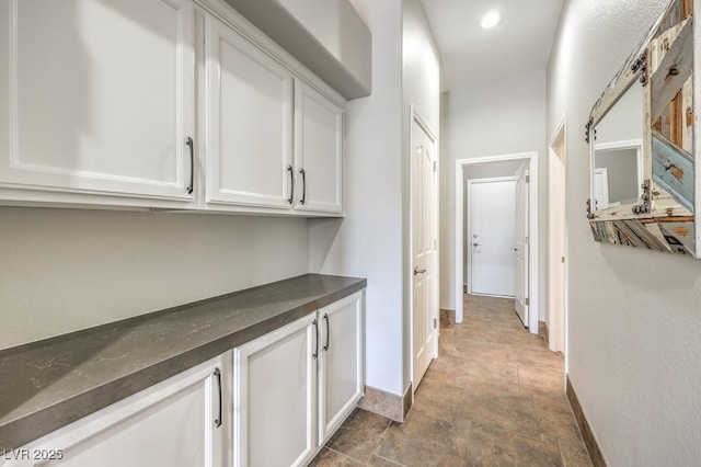 corridor featuring baseboards and stone finish floor