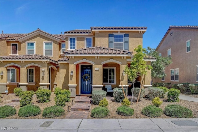mediterranean / spanish house featuring a porch, stucco siding, and a tile roof