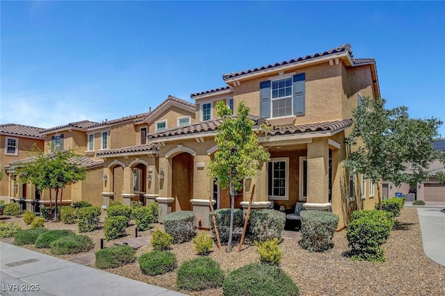 mediterranean / spanish-style house featuring a tiled roof, a porch, and stucco siding