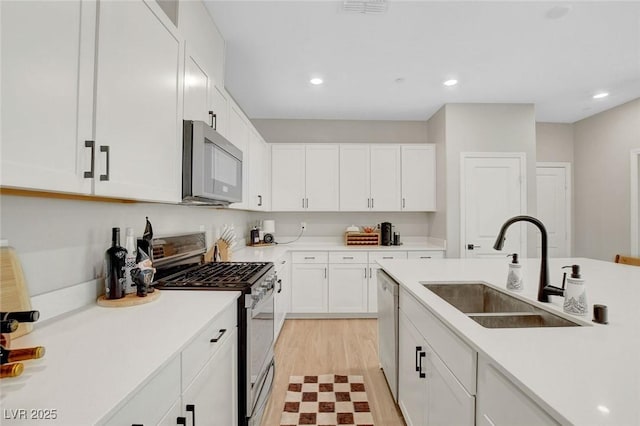kitchen featuring a sink, appliances with stainless steel finishes, white cabinets, and light countertops