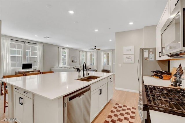 kitchen featuring an island with sink, light wood-type flooring, recessed lighting, a sink, and dishwasher
