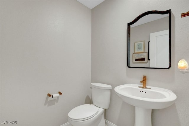 bathroom featuring a sink, baseboards, and toilet