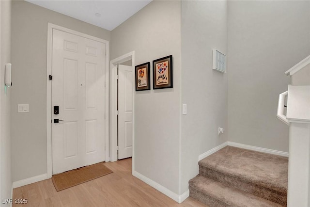 entrance foyer with light wood-style floors, baseboards, and stairway