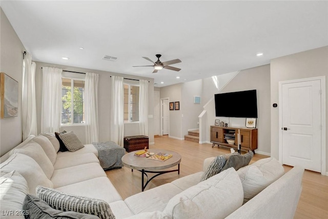 living room with stairway, a ceiling fan, light wood finished floors, and visible vents
