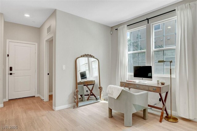 home office with baseboards, light wood-type flooring, and visible vents