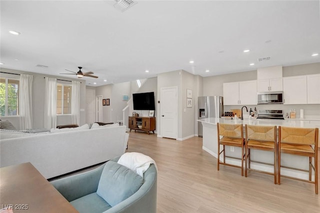 living area with light wood-type flooring, recessed lighting, a ceiling fan, and visible vents