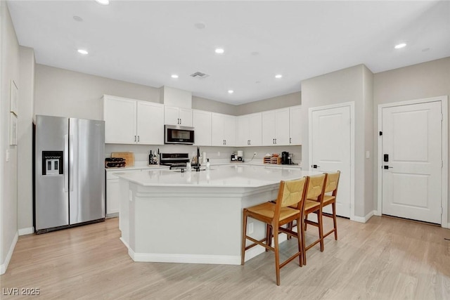 kitchen with visible vents, light countertops, light wood finished floors, stainless steel appliances, and white cabinetry