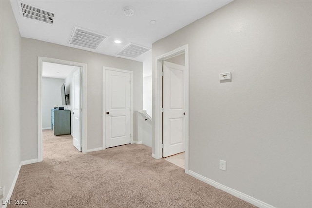 hallway with baseboards, light carpet, and visible vents