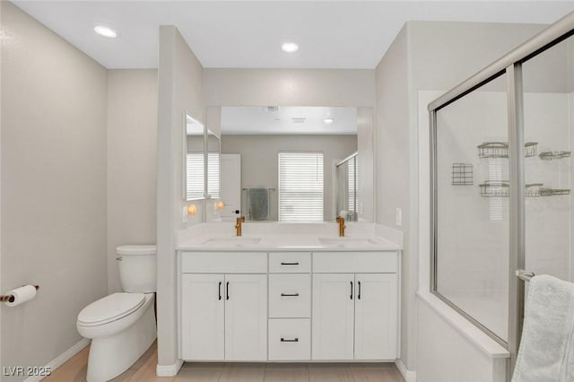 full bathroom featuring double vanity, toilet, a shower stall, and a sink