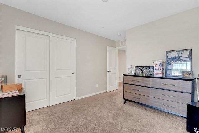 bedroom featuring baseboards, light colored carpet, visible vents, and a closet