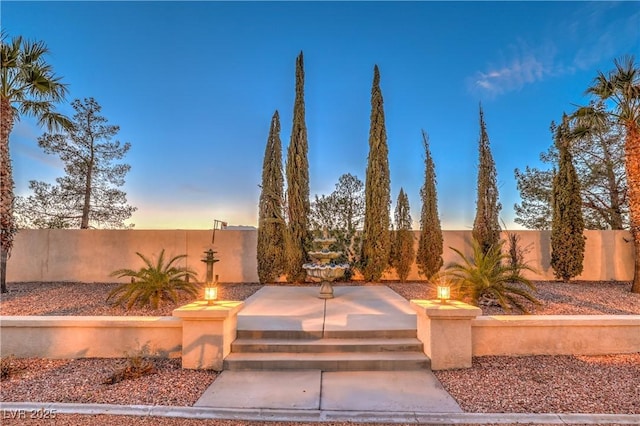 patio terrace at dusk featuring a fenced backyard