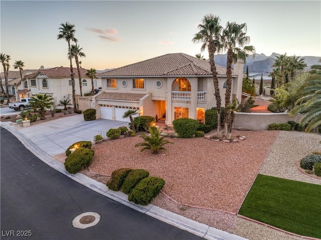 mediterranean / spanish-style home with driveway, stucco siding, an attached garage, a balcony, and a tile roof