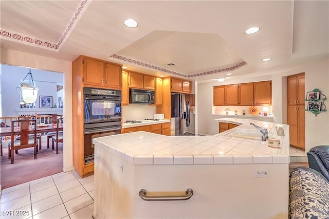 kitchen featuring black appliances, a sink, a raised ceiling, light tile patterned floors, and light carpet