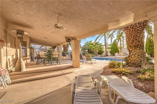 view of patio / terrace with outdoor dining area, a ceiling fan, and an outdoor pool